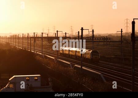 Kurze erste Great Western Bahn 'Castle Class' Intercity 125, die Coedkernew an der South Wales Hauptstrecke mit einem lokalen Haltezug bei Sonnenuntergang passiert Stockfoto