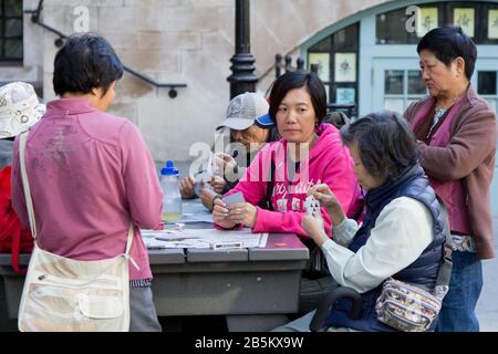 Ältere Frauen spielen Kartenspiele außerhalb von Chinatown, New York Stockfoto