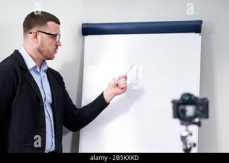 Junge Videoblogger präsentieren wichtige Daten zu leerem Flipchart-Mockup, Online-Bildungskonzept Stockfoto