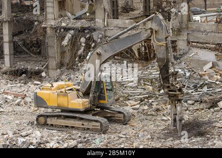 Hydraulik-Scherenbagger sortiert Altmetall an der Baustelle. Stahlbetonkonstruktionen. Abriss eines Gebäudes Stockfoto