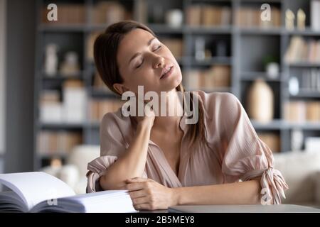 Junge gestresste Frau, die unter Nackenschmerzen leidet. Stockfoto