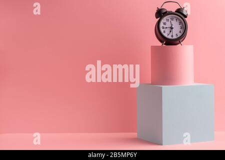 Vintage-Wecker auf Würfel und Zylinder auf pinkfarbenem Hintergrund Stockfoto
