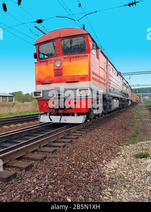 Rote Diesellokomotive auf den Gleisen in Bewegung gegen einen blauen Himmel Stockfoto