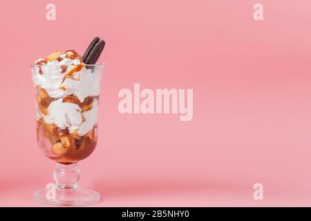 Süßes Dessert im Glas mit Keks und Schlagsahne auf Rosa bsckground, selektiver Fokus und Leerzeichen Stockfoto