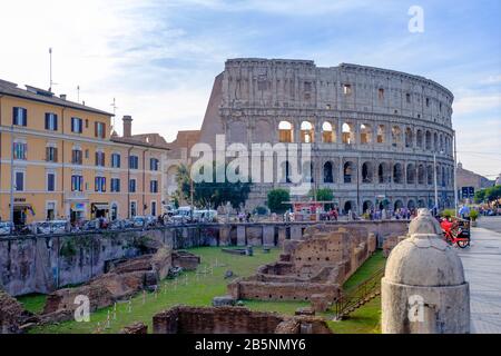Antike Gebäude in Rom, Straßenblick auf die Ruinen von Ludus Magnus, große Gladiatorenschule, mit römischem Kolosseum im Hintergrund, Rom, Italien. Stockfoto