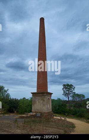 Die hohe, rote Ziegelsteinrauchsteinruine im alten Beehive-Bergbaugebiet. In Maldon, Victoria, Australien. Stockfoto