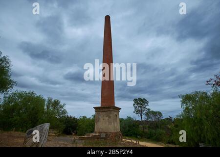 Die hohe, rote Ziegelsteinrauchsteinruine im alten Beehive-Bergbaugebiet. In Maldon, Victoria, Australien. Stockfoto