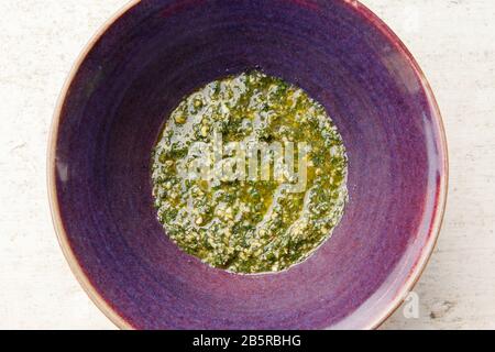 Basil Pesto in Purple Bowl von oben auf White Surface Stockfoto