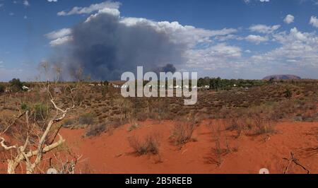 Eine riesige Wolke von Buschfeuer Rauch größer als Uluru, beide aus dem Blick auf Ayres Rock Resort, Yulara, Northern Territory, Australien. Stockfoto