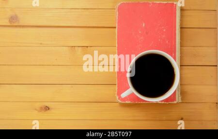 Draufsicht, EINE Tasse Kaffee und geschlossenes rotes Buch auf Holzhintergrund Stockfoto