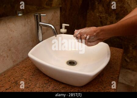 Ein Junge wäscht die Hände in einem Waschbecken mit Seife und fließendem Wasser. Das Händewaschen ist ein wichtiger Schritt bei der Vorbeugung des Kovid-19-Coronavirus Stockfoto