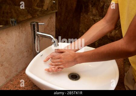 Ein Junge wäscht die Hände in einem Waschbecken mit Seife und fließendem Wasser. Das Händewaschen ist ein wichtiger Schritt bei der Vorbeugung des Kovid-19-Coronavirus Stockfoto