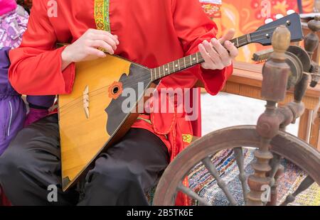 Der Musiker spielt ein russisches Volksmusikinstrument, eine Balalaika, in einem uralten Nationaltracht Stockfoto