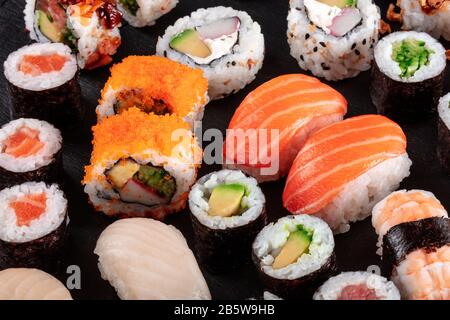 Großes Sushi in Schwarz. Eine Auswahl an verschiedenen Maki, Nigiri und Brötchen Stockfoto