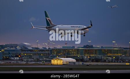 Richmond, British Columbia, Kanada. März 2020. Eine WestJet Airlines Boeing 737-800 (C-GZWS) mit einem Gang landet in der Abenddämmerung, Vancouver International Airport, Samstag, 7. März 2020. Kredit: Bayne Stanley/ZUMA Wire/Alamy Live News Stockfoto