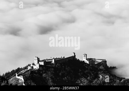Ein epischer Blick auf die Kirche St. Franziskus und Rocca Maggiore in der Stadt Assisi (Umbrien) über einem Nebelmeer Stockfoto