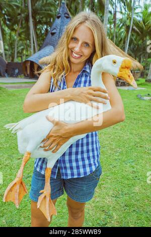 Junge Frau in den Händen halten, Funny Farm pet - Große weiße Hausgans. Tag Tour auf Familie Sommerurlaub mit Kindern. Stockfoto