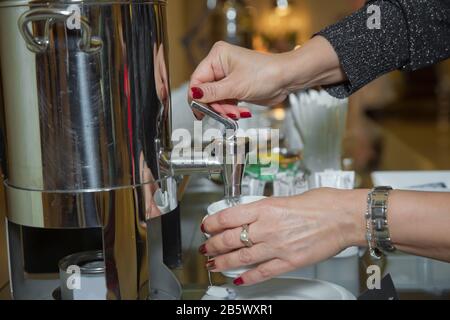 Kaffeespresso auf der Hand. Hand mit frischem schwarzem Kaffee Aus der Kaffeemaschine. Professionelle Espressomaschine mit kräftigem, frisch aussehenden Design Stockfoto