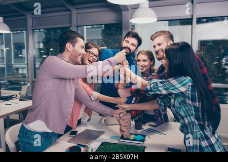 Fröhliche Geschäftsleute, die ihre Faust übereinander legen und lachen. Sie haben eine Schulung Stockfoto