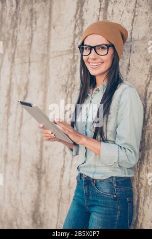 Porträt einer glücklichen Hüftfrau mit Tablette in der Nähe der Steinwand Stockfoto