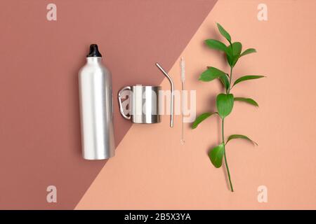 Grüne Blätter, Flasche, Metallrohr und Reinigungsbürste. Kein Abfallzubehör für das Trinken auf braunem Grund. Stockfoto