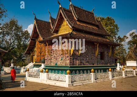 Das Rückstellende Buddha-Heiligtum (rote Kapelle) mit der Haupt-sim hinter Luang Prabangs prächtigem Tempel Wat Xieng Thong. Stockfoto