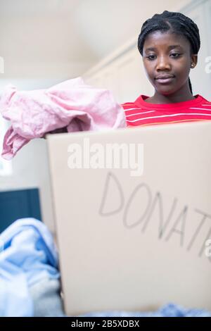 Teenager-Mädchen, Das Unerwünschte Kleidung In Box Für Die Charity Collection Einbringt
