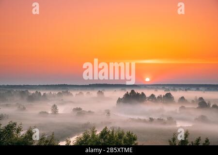 Erstaunlich Sonnenaufgang Sonnenuntergang über neblige Landschaft. Malerischer Blick auf Nebligen Morgen Sky mit der aufgehenden Sonne über dem nebligen Wald und Fluss. Anfang Sommer Natur von Eas Stockfoto