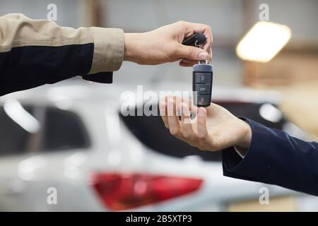 Horizontale Nahaufnahme der Hand von Auto mechinc, die Autoschlüssel an nicht erkennbaren Besitzer gibt, Kopierraum Stockfoto
