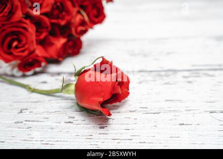 Ein Blumenstrauß aus scharlachroten Rosen für das Valentinstags-Verzierungen-Konzept mit weißem Holzhintergrund. Liebe und Romantik Stockfoto