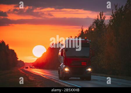 Roter Stapler Oder Traktoreinheit, Prime Mover, Fahreinheit In Bewegung Auf Der Straße, Freeway. Asphalt Motorway Highway Vor Dem Hintergrund Von Big Sunset Sun Busin Stockfoto