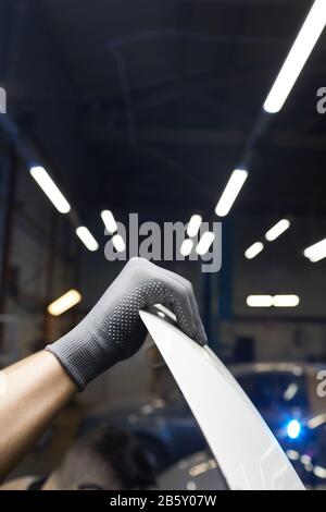 Vertikaler Nahaufnahme der männlichen Hand in der grauen Handschuhöffnung in der Auto-Service-Zentrale, Kopierraum Stockfoto