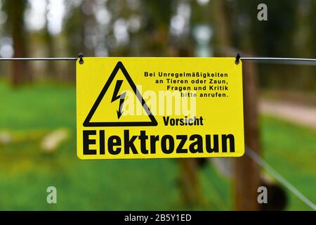 Gelbes Warnschild Elektrozaun mit deutschem Text "Achtung, Elektrozaun" Stockfoto