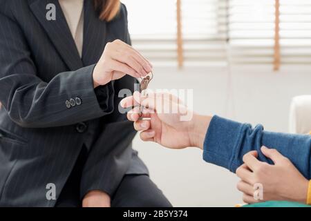 Asiatisches glückliches Paar erhält Schlüssel und Handschlag mit Realtor-Agent mit lächelndem Gesicht in neuem Haus.Kauf neuer Hausimmobilien Stockfoto