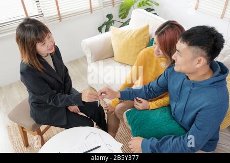 Asiatisches glückliches Paar erhält Schlüssel und Handschlag mit Realtor-Agent mit lächelndem Gesicht in neuem Haus.Kauf neuer Hausimmobilien Stockfoto