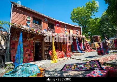 Helle, sonnige Aussicht auf das traditionelle Holzgebäude mit farbenfrohen türkischen Teppichen für Touristen in einer ruhigen Straße in Istanbul, Türkei Stockfoto