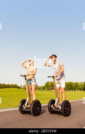 Glücklicher Mann und Frau auf segway und auf der Suche nach dem Weg Stockfoto