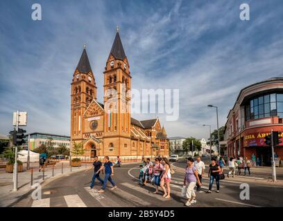 Fußgänger, die die Straße in der Nähe der Römisch-katholischen Kathedrale im neuromanischen Stil überqueren, in Nyiregyhaza, Szabolcs-Szatmar-Bereg, Ungarn Stockfoto