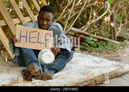 Junger obdachloser Afrikaner mit Pappschild, der um Hilfe bittet Stockfoto