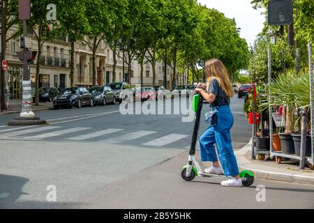 Frankreich. Sommerlicher sonniger Tag in Paris. Mädchen auf einem elektrischen Roller an einer Straßenkreuzung Stockfoto