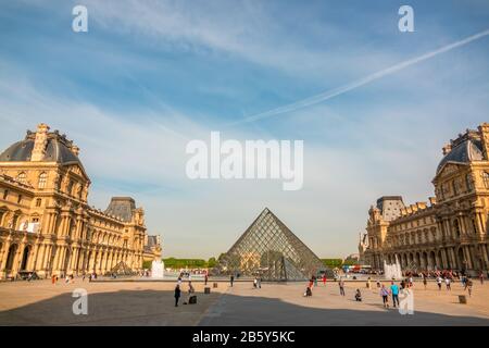 Frankreich. Sommerlicher sonniger Tag in Paris. Innenhof des Louvre Museums mit Springbrunnen und blauem Himmel. Glaspyramide und Touristen Stockfoto