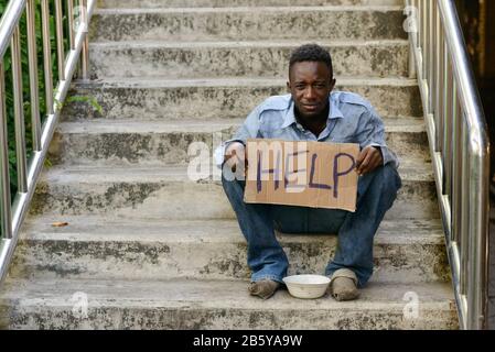 Junger obdachloser Afrikaner mit Pappschild, der um Hilfe bittet Stockfoto