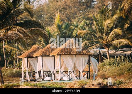 Goa, Indien. Gartenlaubenzelte Mit Straßendach Für Touristen Am Strand Mit Tischen Und Sonnenliegen Im Inneren. Stockfoto