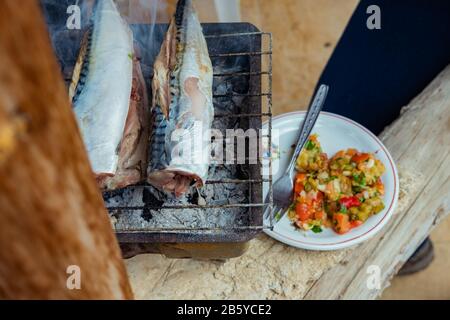 Fische (Makrelen) auf dem Grill im Garten. Mit Salatplatte in der Nähe. Stockfoto