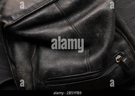 Schwarzer Hintergrund - alte zerknitterte Ledertasche mit Reißverschluss-Verschluss in der Nähe. Stockfoto