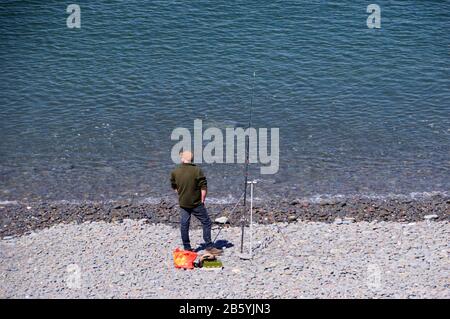 Man Angelt am Kieselstrand in Babbacombe Mouth in der Nähe von Buck's Mills am South West Coast Path, North Devon, Großbritannien. Stockfoto