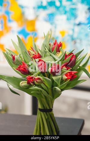 Blumenstrauß mit roten Tulpen auf hellem Hintergrund. Grußkarte der Feder . Roter Blumenstrauß mit Tulpen im blauen und gelben Hintergrund. Stockfoto