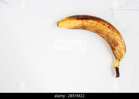 Alte bräunlich verdunkelte Banane in einer Haut. Hässliches Essen. Dunkle Bananen verdorben im Laufe der Zeit auf weißem Hintergrund. Horizontale Ausrichtung, Seitenansicht. Stockfoto
