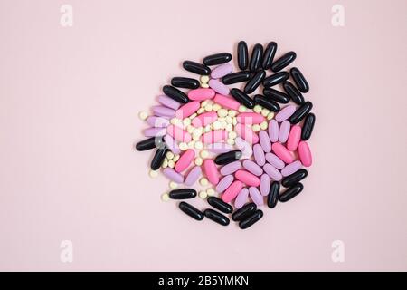 Verstreute bunte Pharma-Pillen auf einem rosafarbenen Hintergrund. Antibakterielle Kapsel mit Antibiotika. Kreative Idee. Medizin. Drogen. Traurig. Matrize. Stockfoto