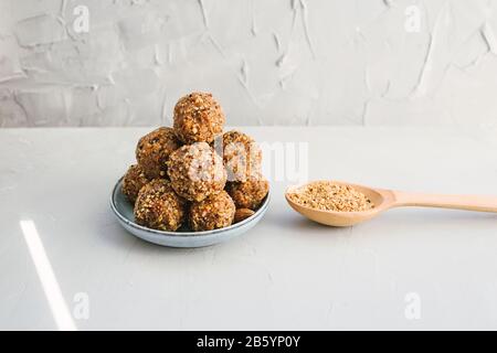 Hausgemachte Energiekugeln mit getrockneten Aprikosen, Rosinen, Datteln, Walnüssen, Mandeln und Kokosnuss. Gesundes süßes Essen mit Nussspänen. Vegane vegetarische rohe sn Stockfoto